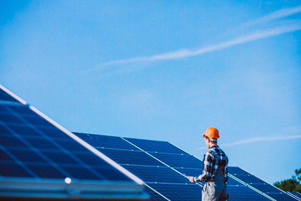 Imagem de um rapaz trabalhando em um conjunto de painéis de captação solar. A imagem faz relação com o artigo sobre os benefícios do SAP Business One para empresas de energia.